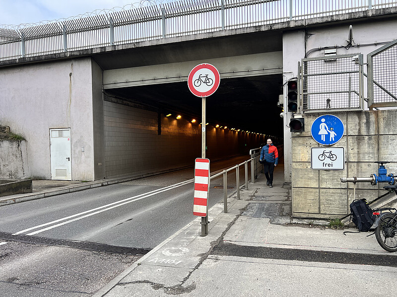 Bild zeigt den Eingang zum Fahrradtunnel mit Verkehrsschildern davor