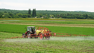 Landwirt mit Traktor sprüht Pestizide oder Dünger auf das Feld