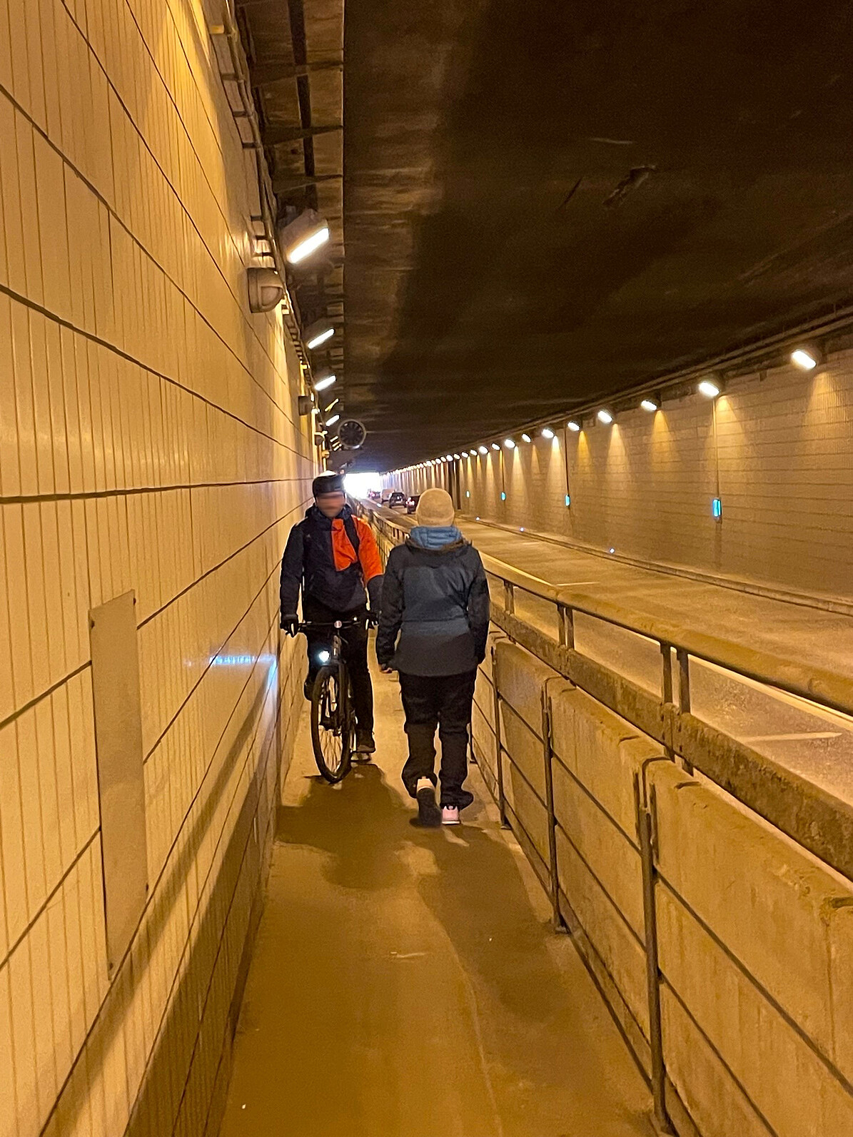 Bild zeigt den Flughafentunnel mit einem Fahrradfahrer und einer entgegen kommenden Fußgängerin