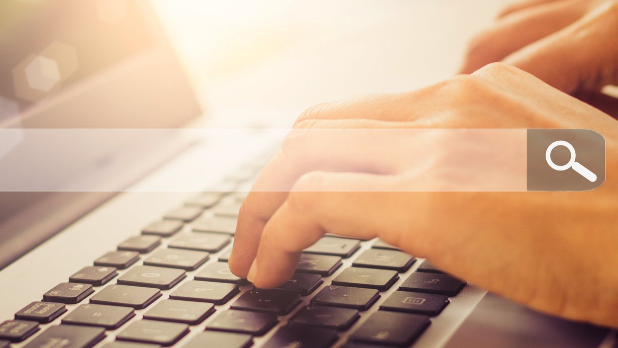 Frauenhände geben einen Suchbegriff auf dem Laptop ein