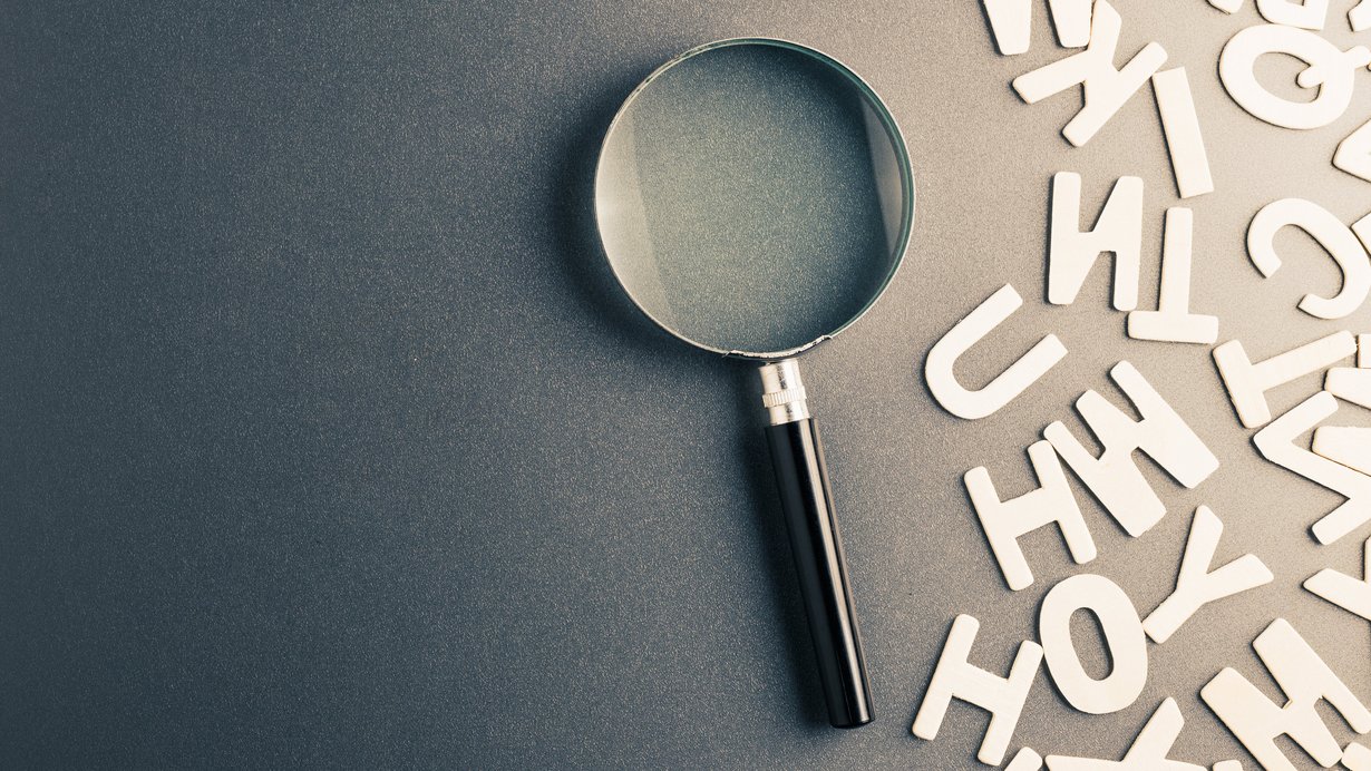 Symbolbild: Lupe mit Buchstaben