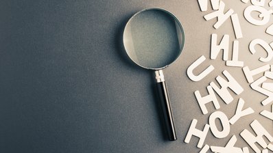 Symbolbild: Lupe mit Buchstaben