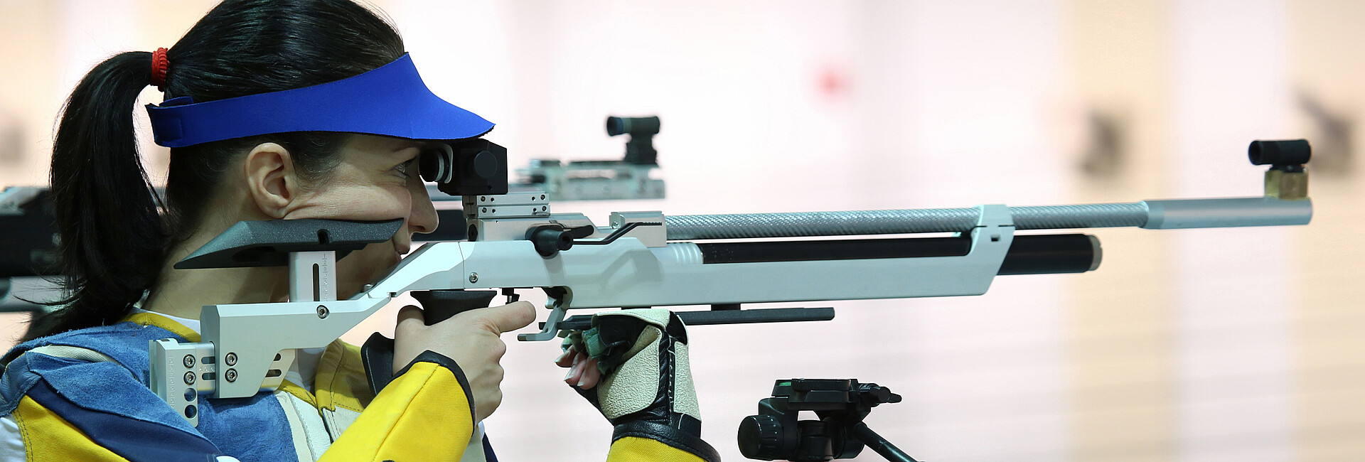 Eine Sportschützin zielt mit einem Luftgewehr auf eine Zielscheibe