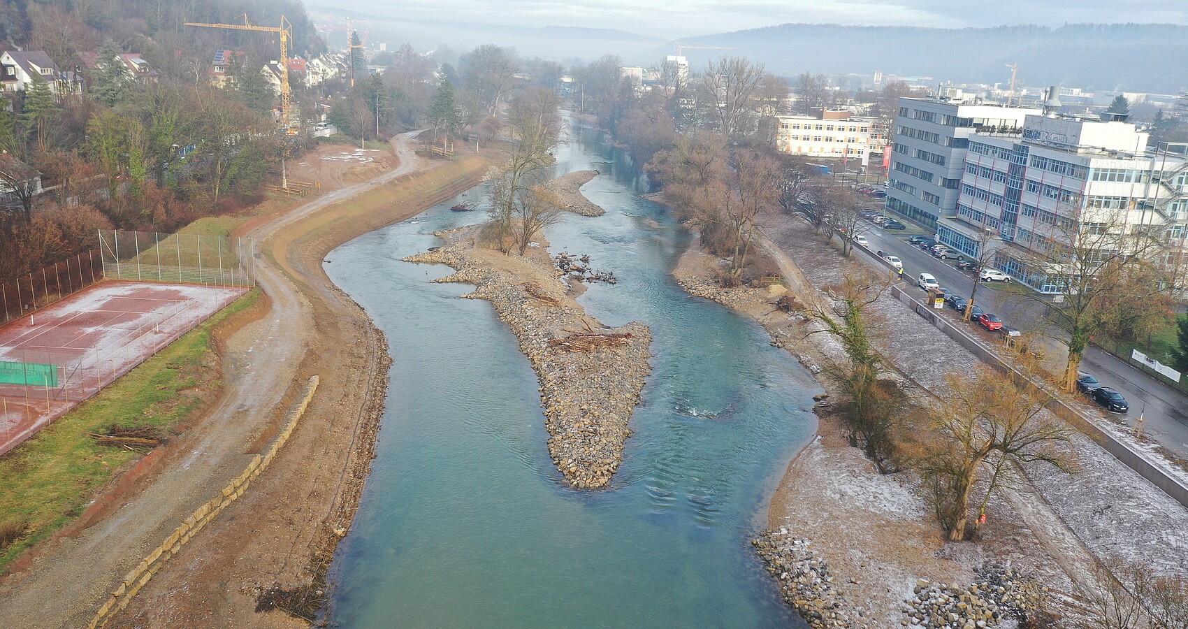 Blick im Januar von oben auf die Baustelle des Flussparks Neckaraue - im Mittelpunkt ist eine Kiesinsel im blauen Neckar zu sehen 