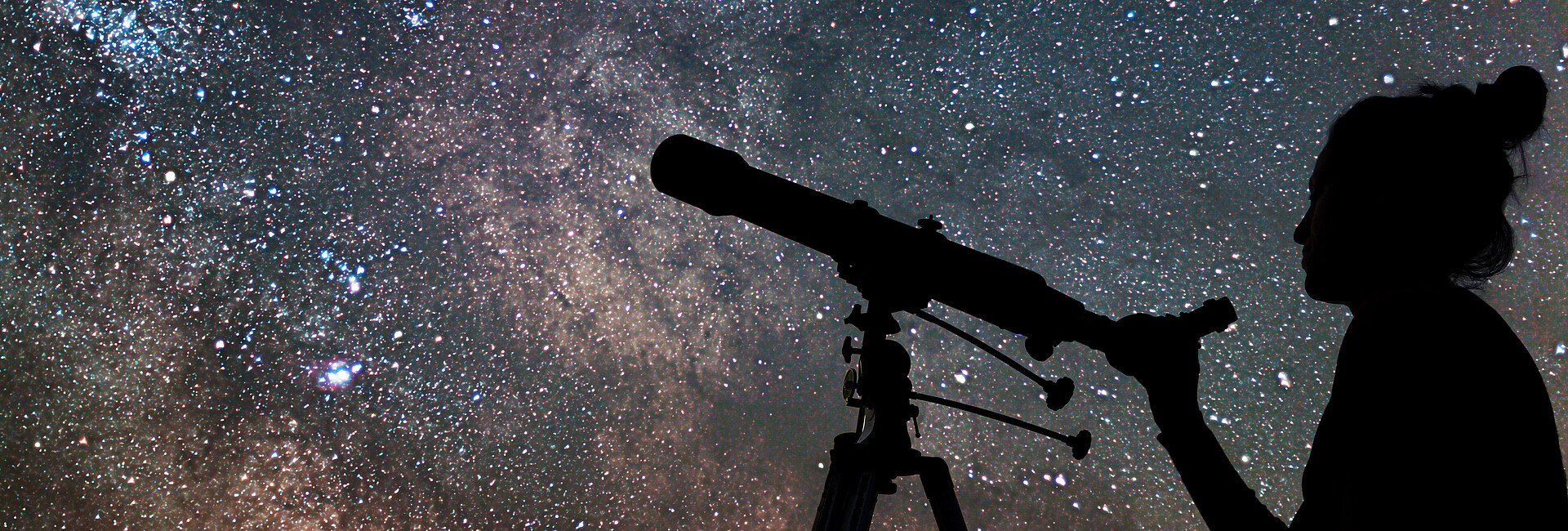 Schattenbild einer jungen Frau und eines Teleskops. Die Frau beobachtet die Sterne am nächtlichen Himmel.
