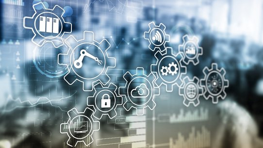 Im Hintergrund sieht man eine Großraumbüro, im Vordergrund sind Symbole zu sehen, die das Thema Wirtschaft thematisieren