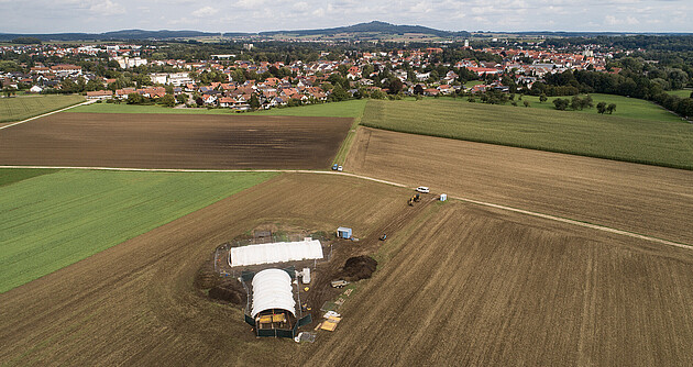 Drohnenaufnahme mit der Grabungsstätte im Vordergrund, Riedlingen im Mittelgrund und dem Bussen im Hintergrund