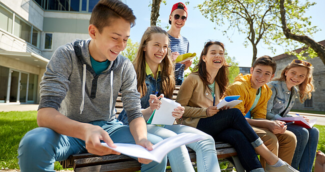 Schülerinnen und Schüler in der Pause, lachend auf einer Bank