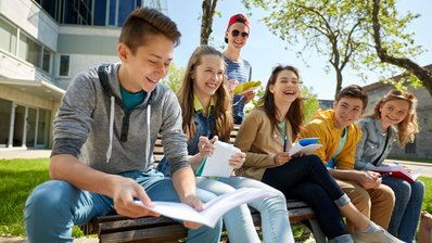 Schülerinnen und Schüler in der Pause, lachend auf einer Bank