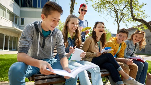 Schülerinnen und Schüler in der Pause, lachend auf einer Bank