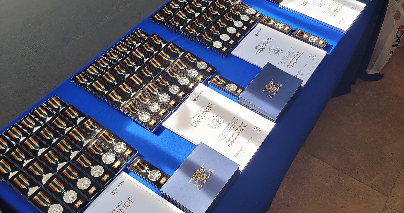Medaillen und Urkunden liegen auf einem Tisch mit blauem Tischtuch