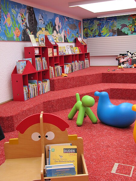 Rote Sitzstufenlandschaft mit Bilderbuchtrögen in der Kinderbücherei der Stadtbücherei Albstadt-Ebingen