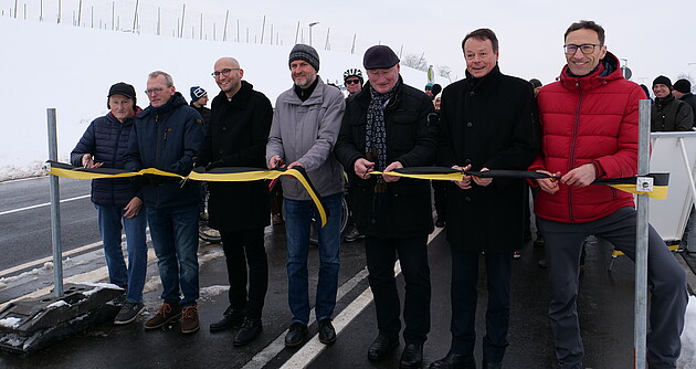 Das Foto zeigt sieben Männer beim Banddurchschnitt bei der offiziellen Verkehrsfreigabe des neuen Radwegs entlang der L 335 zwischen Grünkraut und Sigmarshofen