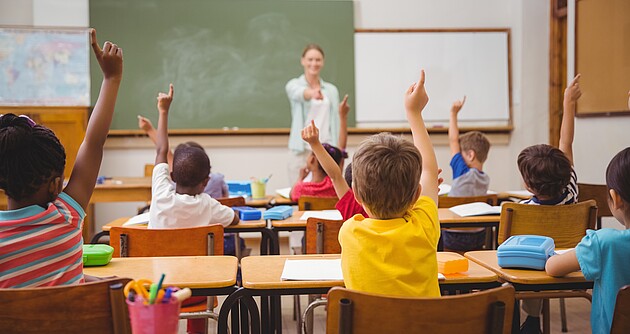 Schülerinnen und Schüler während des Unterrichts, im Hintergrund die Lehrerin