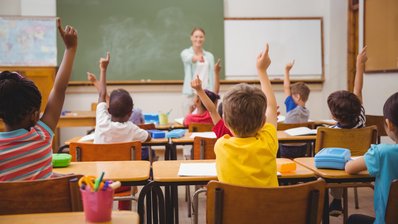 Schülerinnen und Schüler während des Unterrichts, im Hintergrund die Lehrerin