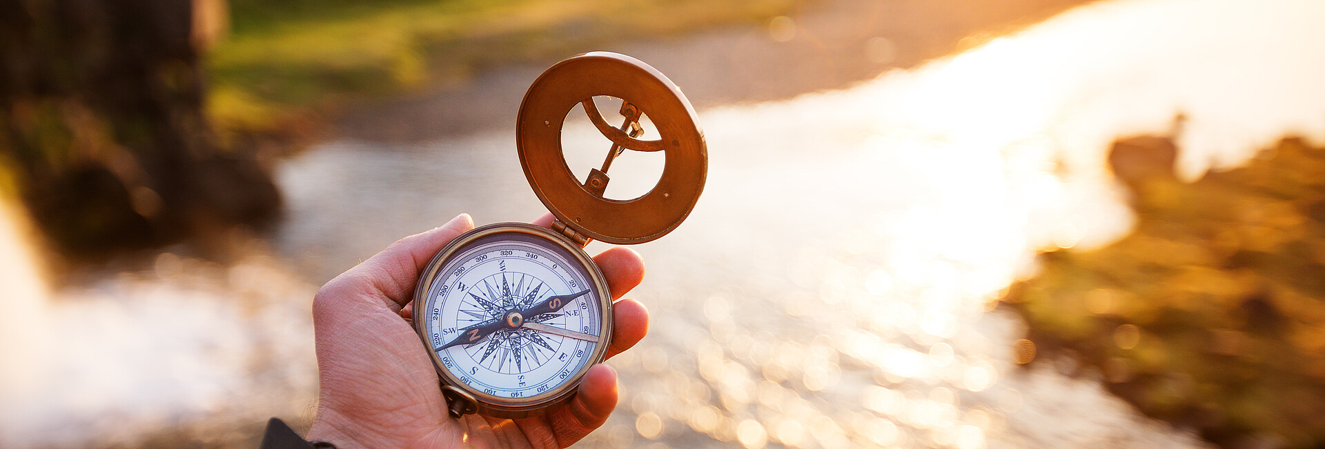 Landschaft mit altem Kompass auf der Hand des Reisenden. 