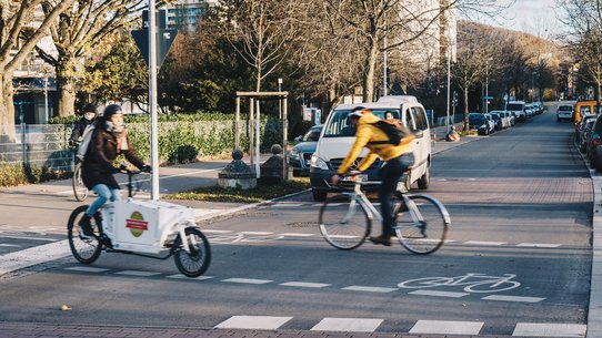 Bild zeigt 2 Fahrradfahrer beim Überqueren einer Straße