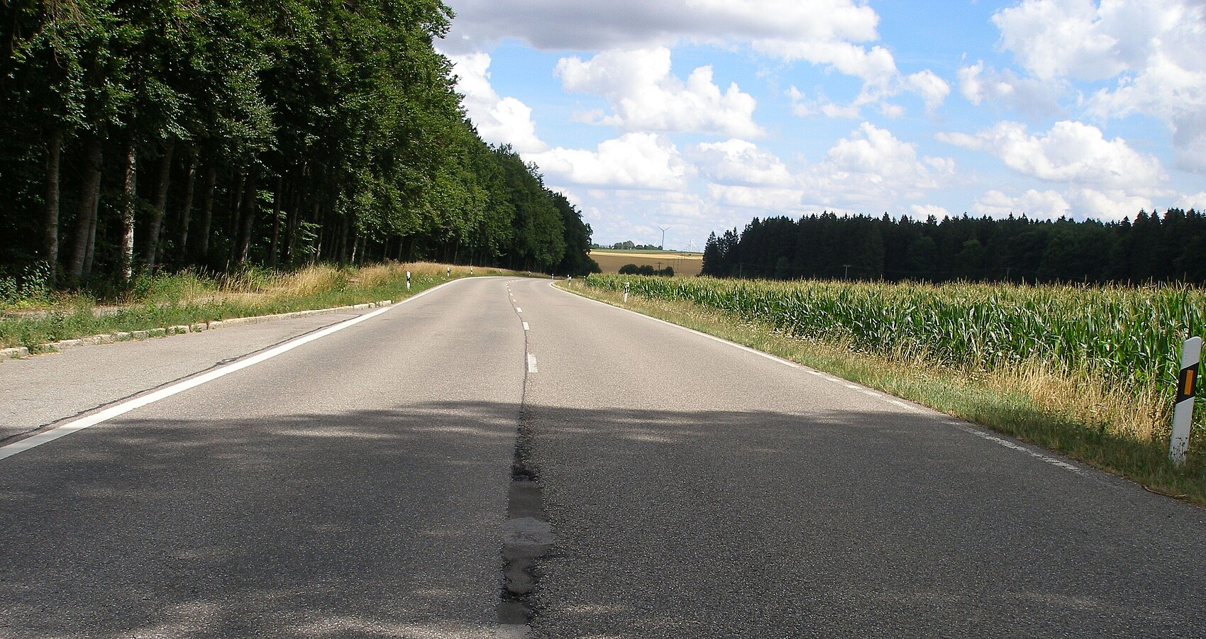 Das Bild zeigt ein gerades beschädigtes Stück der B 28; links sieht man eine Haltebucht und rechts ein Maisfeld
