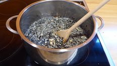 Körner im Topf; im Topf befindet sich ein Rührlöffel