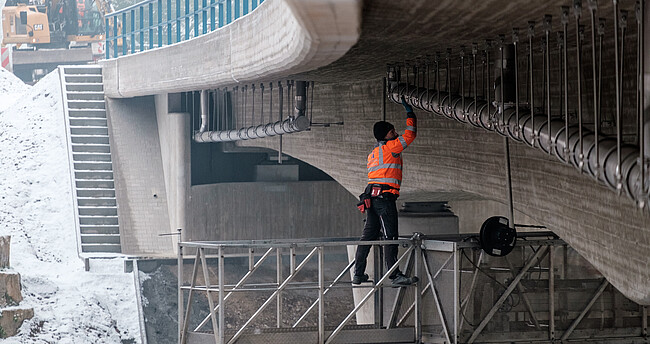 Prüfung einer Brücke: Ein Ingenieur steht auf einem Hubwagen und kontrolliert die Brücke