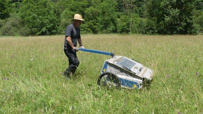 Mann mit Samenerntegerät auf Wiese