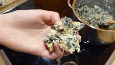 Das Vogelfutter wird mit der Hand geformt; der Topf mit dem Vogelfutter steht auf dem Herd