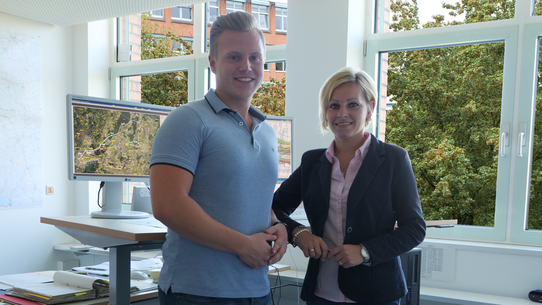 Bauzeichnerin und Bauzeichner stehen am Tisch im Büro