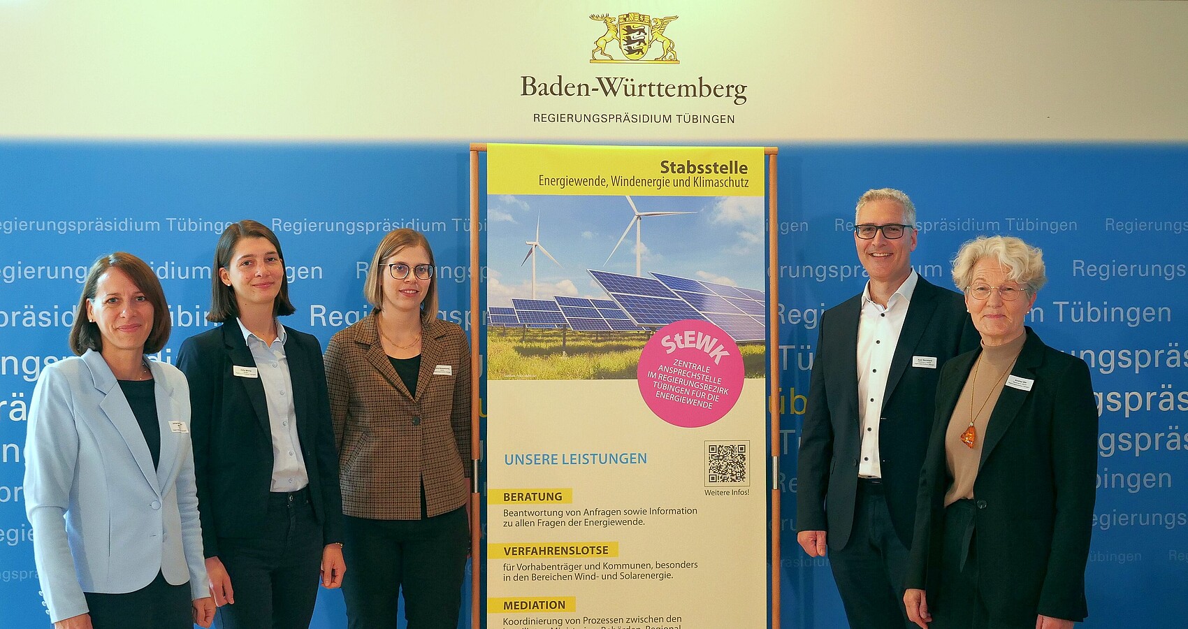 4 Frauen und ein Mann neben dem Plakat der Stabsstelle Energiewende, Windenergie und Klimaschutz