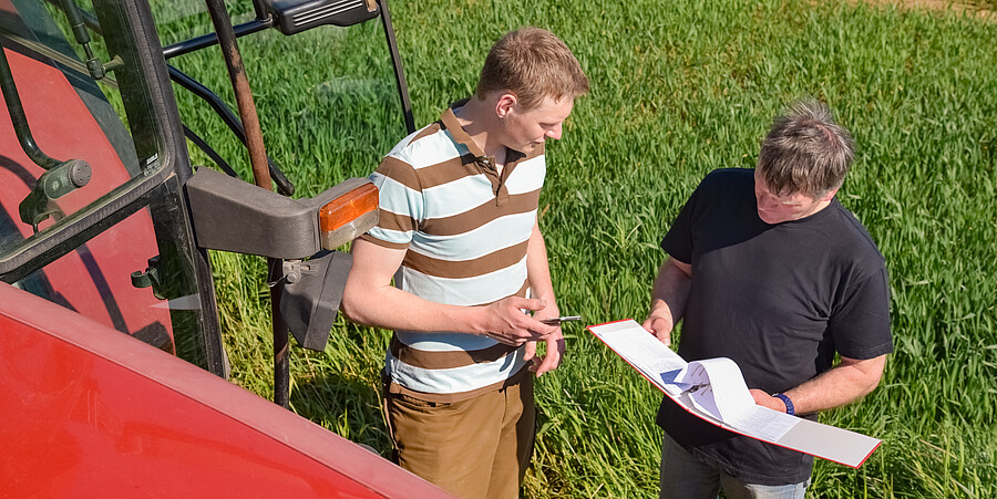 Landwirt und Mitarbeiter besprechen sich auf dem Feld