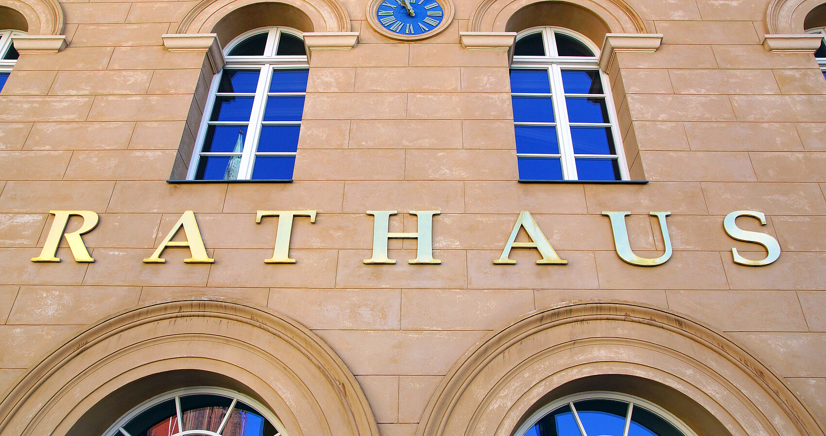 Fensterfront eines Rathauses mit Schriftzug über der Tür