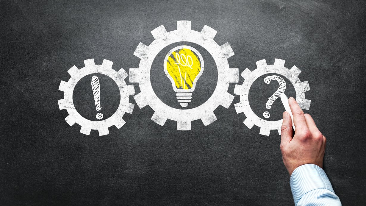 man sieht drei Zahnräder als Symbole für den Wirtschaftsmotor, im ersten sieht man ein Ausrufzeichen, im zweiten eine brennende Glühbirne, im dritten schreibt eine Hand ein Fragezeichen rein