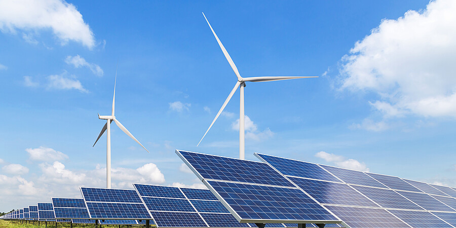 Windkraft und Photovoltaik Eine Windkraftanlage auf der Wiese, darunter steht eine Photovoltaikanlage