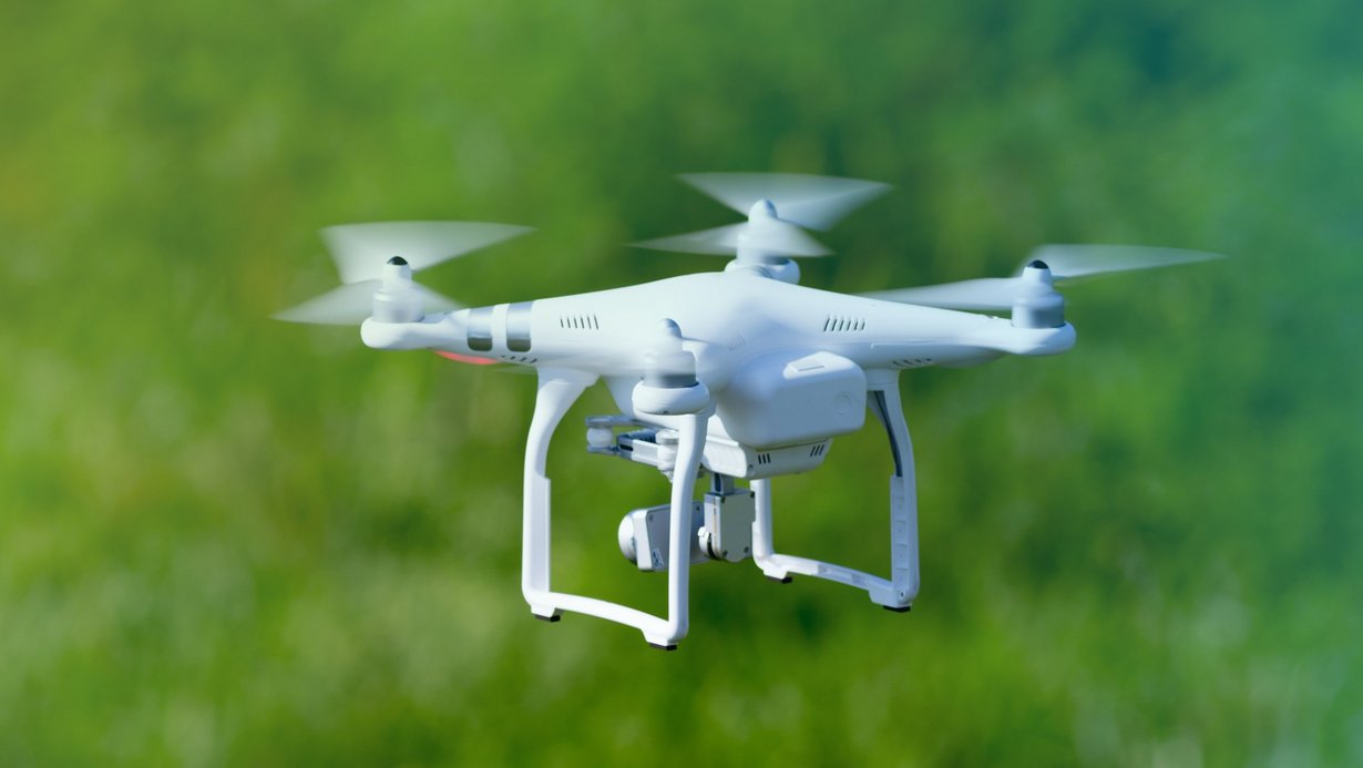 Quadcopter Drohne fliegt über ein Feld