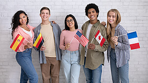 Mehrere Schülerinnen und Schüler stehen mit unterschiedlichen Länderfahnen vor einer Wand