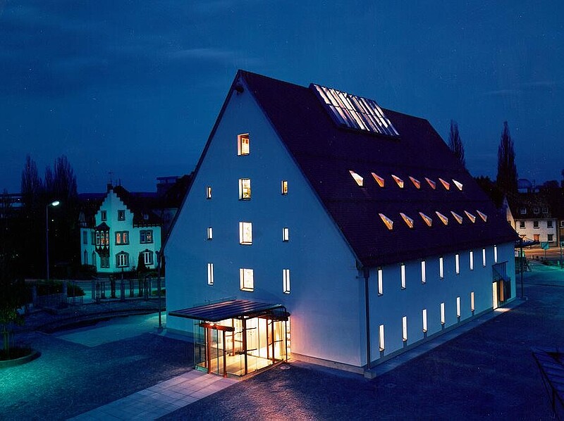 Stadtbücherei Biberach - beleuchtetes Gebäude auf dem Viehmarktplatz bei Nacht