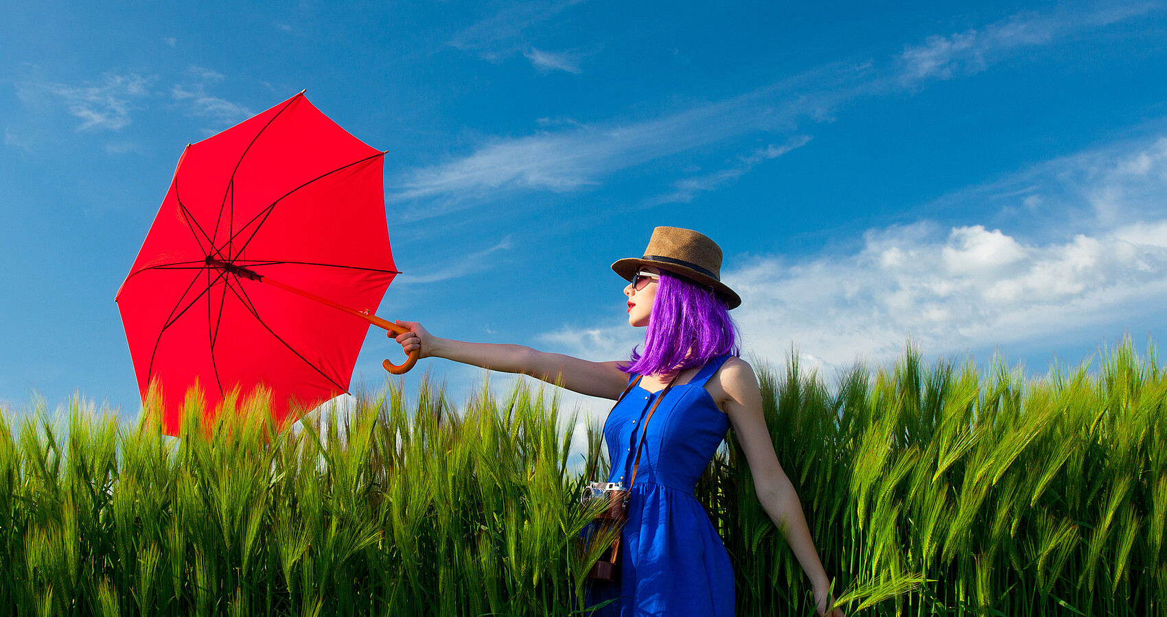 Frau im Getreidefeld mit rotem Schirm