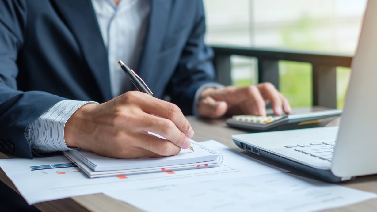 Bürostituation - Mitarbeiter sitzt am Schreibtisch und tippt auf Rechner ein