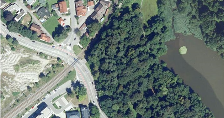 Luftbild; man sieht den Bahnübergang in Wangen, verschiedene Gebäude und ein Gewässer umrahmt von Bäumen