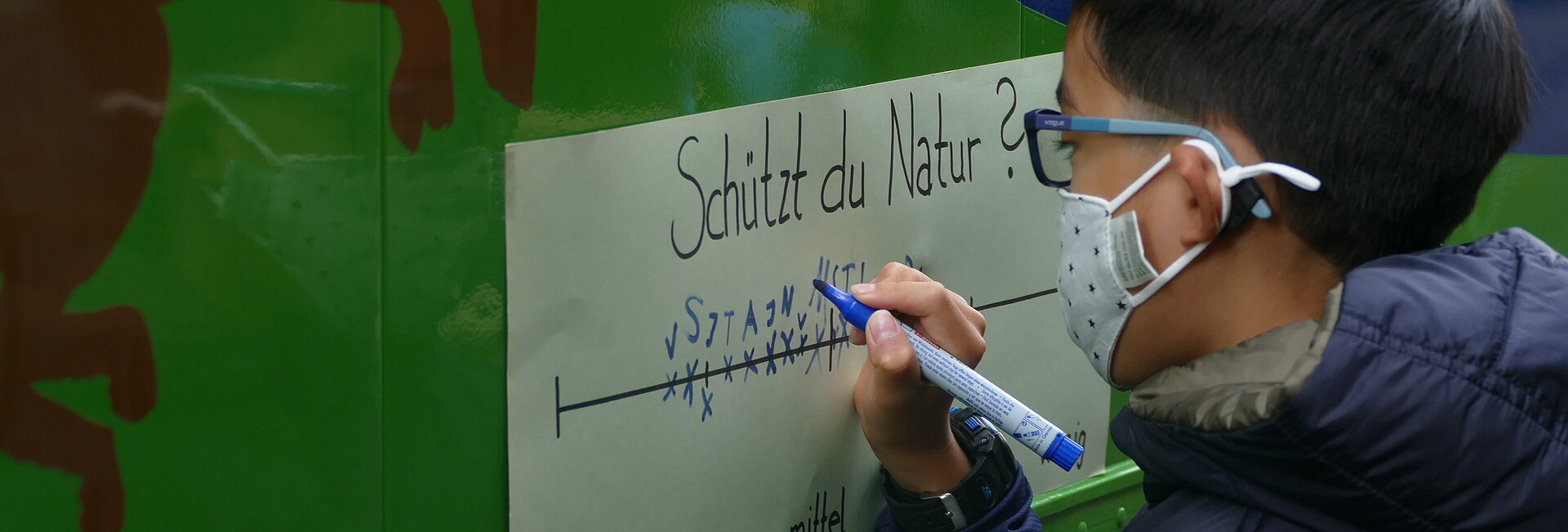 Schützt du die Natur? Junge notiert seine Antwort auf einen Zettel auf dem Ökomobil