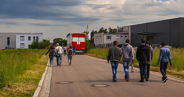 Bild zeigt Flüchtlinge auf einer Straße an der Seite Unterkünfte