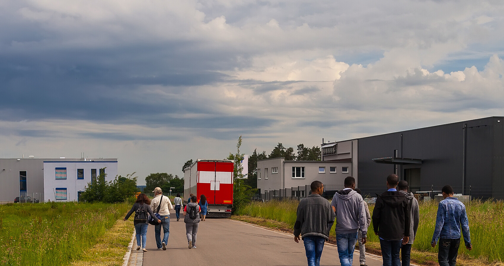 Bild zeigt Flüchtlinge auf einer Straße an der Seite Unterkünfte