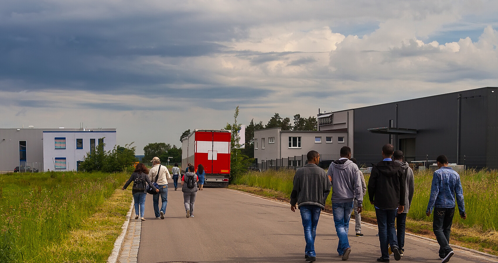 Bild zeigt Flüchtlinge auf einer Straße an der Seite Unterkünfte