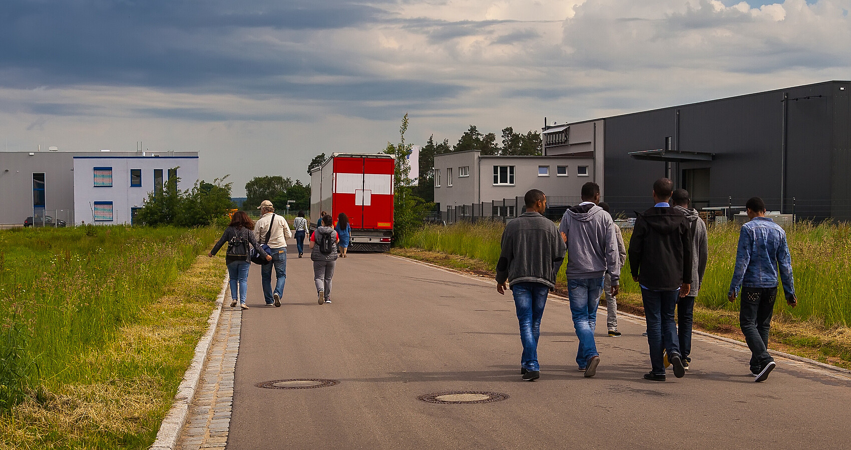 Bild zeigt Flüchtlinge auf einer Straße an der Seite Unterkünfte