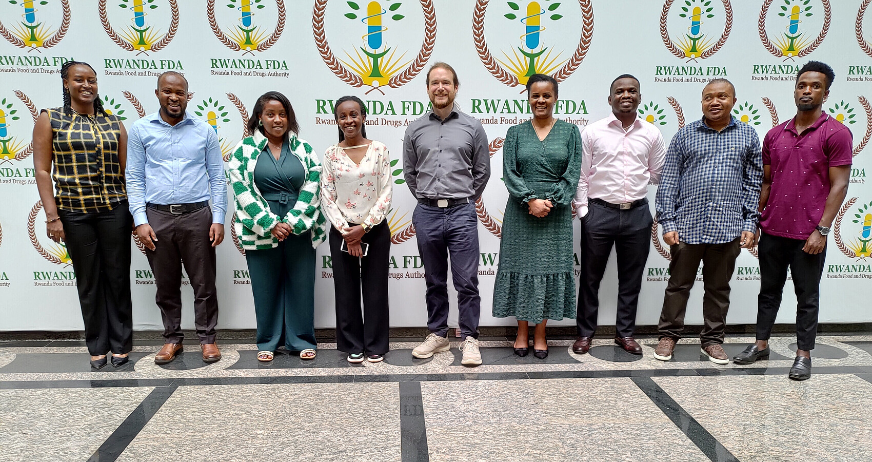 Das Bild zeigt ein Gruppenbild vor einer Pressewand in Ruanda mit teilnehmenden Inspektoren und Inspektorinnen der R-FDA 