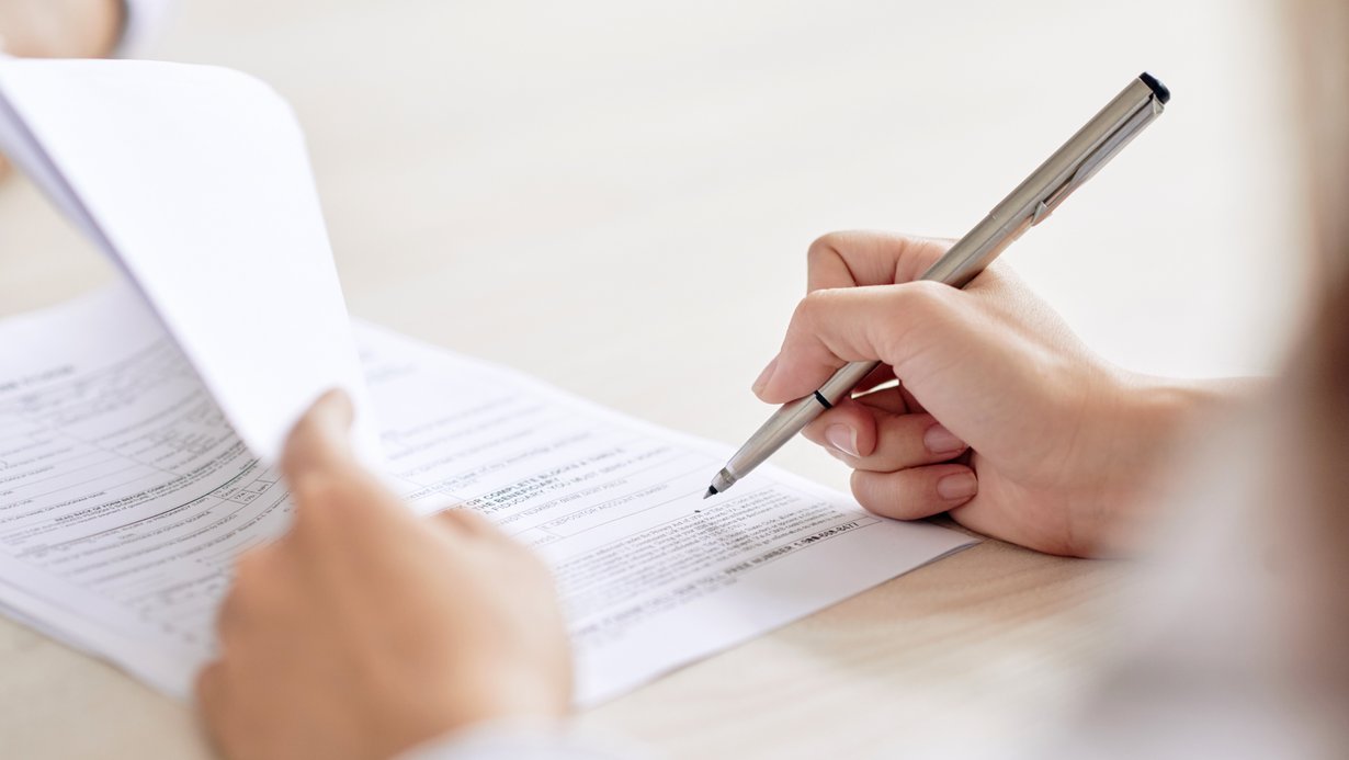Person unterzeichnet einen Vertrag auf dem Schreibtisch