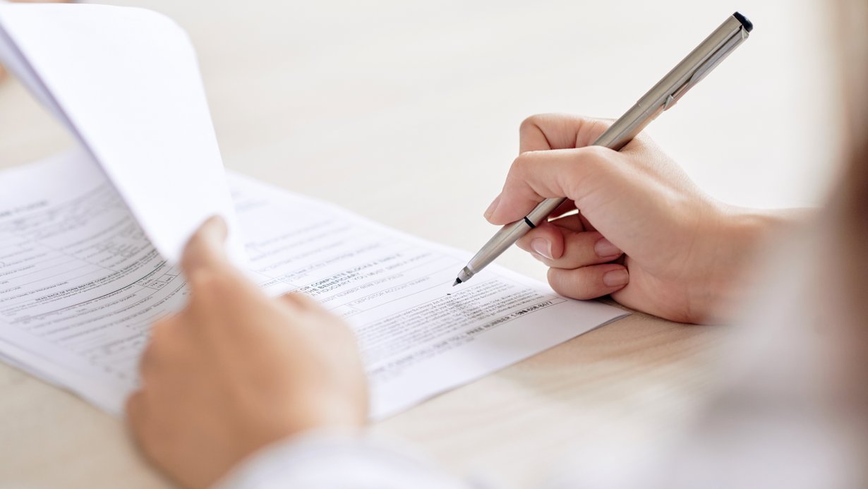 Person unterzeichnet einen Vertrag auf dem Schreibtisch