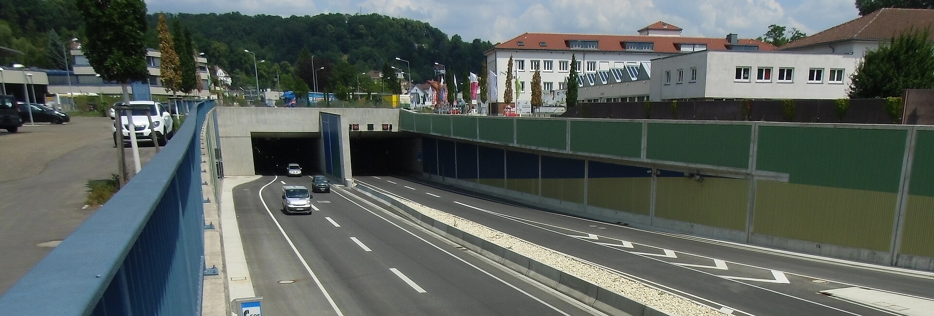 Einfahrt in den Tunnel in Schwäbisch Gmünd, man sieht eine wenig befahrene Straße, die in den Tunnel führt, daneben Gebäude