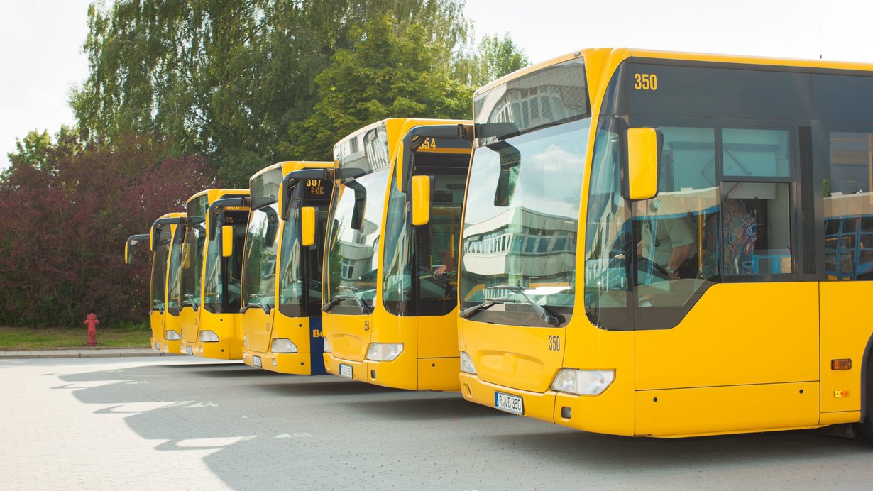 Füng gelbe Buss in einer Reihe im Busbahnhof