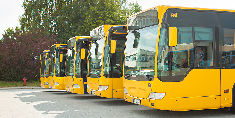 Füng gelbe Buss in einer Reihe im Busbahnhof