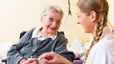 Pflegerin kümmert sich um Seniorin im Altenheim